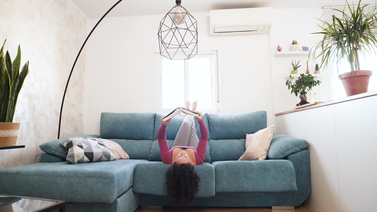 woman lying on her back on the sofa reading a book