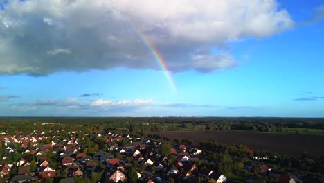 Arco-Iris-En-El-Cielo-Azul,-Gran-Nube-Sobre-El-Pueblo