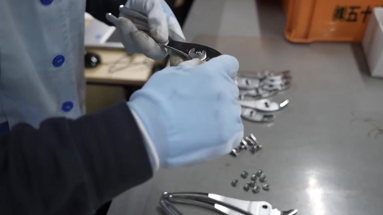 Worker assembling pliers by hand inserting pivot bolt and nut at quality inspection table
