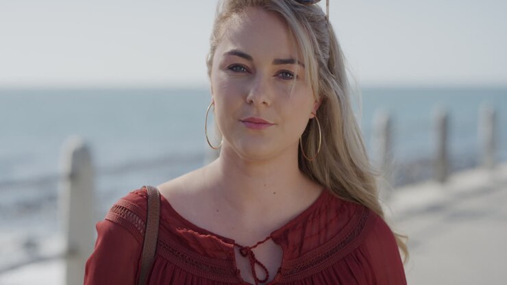 portrait d'une belle jeune femme blonde jouissant d'un style de vie détendu et insouciant. le vent souffle calmement sur les cheveux sur la plage ensoleillée.