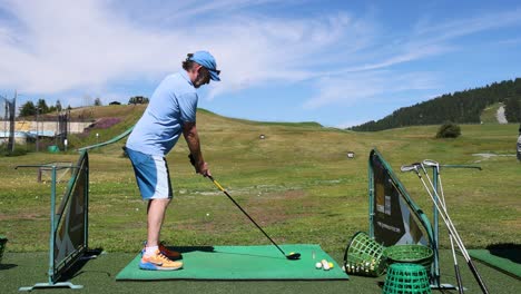 hombre practicando el swing de golf en el campo de manejo