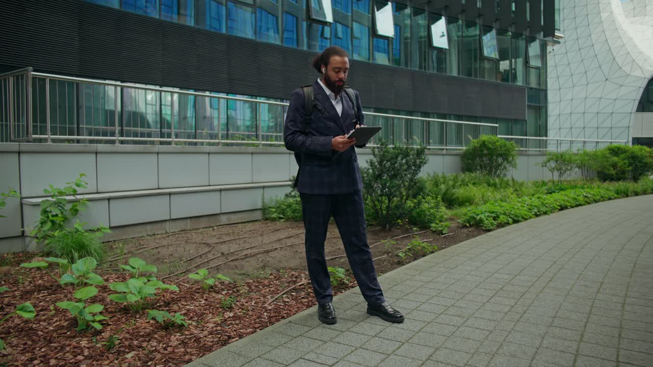 En forretningsmand med en tablet, der står foran en kontorbygning