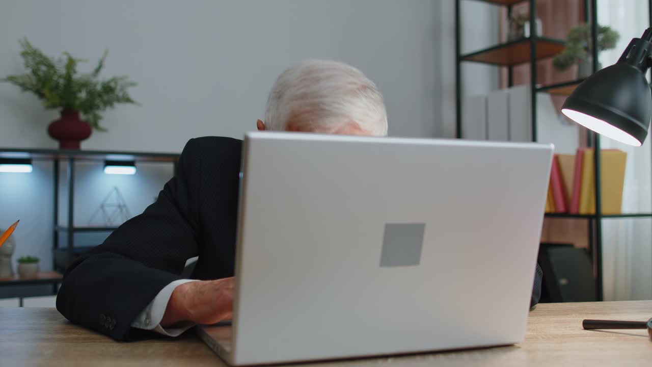 Senior mature older business man hiding behind laptop computer making funny face fooling around