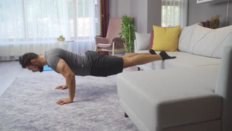 un joven fuerte haciendo flexiones en el suelo de un apartamento moderno.