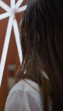 vista trasera de cerca de una mujer joven de cabello largo y marrón caminando en un centro comercial moderno con tiendas minoristas borrosas en el fondo, iluminación cálida y diseño interior elegante