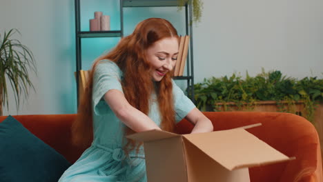 Happy-young-woman-shopper-unpacking-cardboard-box-delivery-parcel-online-shopping-purchase-at-home