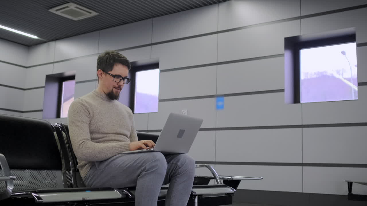 hombre trabajando en una computadora portátil en la sala de espera del aeropuerto