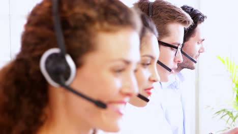 Row-of-call-centre-agents-talking-at-their-desk