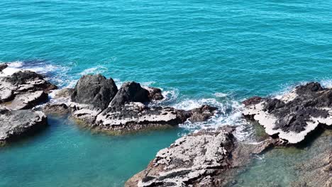 aerial drone footage glides over turquoise coastal waters and rugged rocky outcrops near port douglas, with bright daylight and smooth camera movement