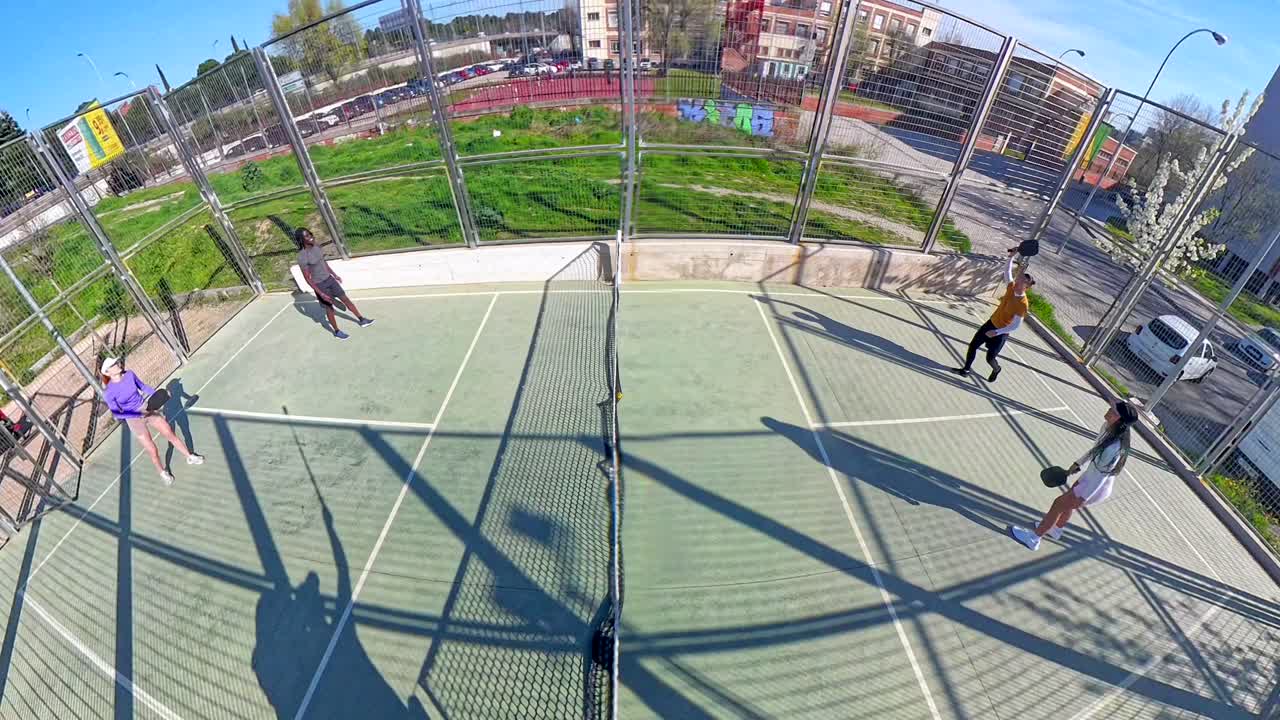 Vista aérea de cuatro amigos jugando pádel en una cancha al aire libre
