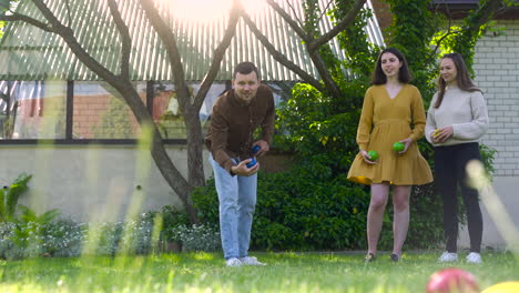 front view of caucasian young man throwing a blue petanque ball in the park on a sunny day