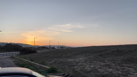 twilight landscape with a view of open land, streetlights lining the road, and a serene sunset in the distance. a blend of nature and urban elements under a pastel sky.