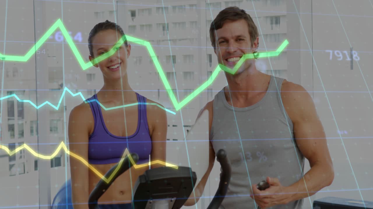 Fitness trainee pedaling bike as coach timing and pointing, raising effort, graphs tracking data