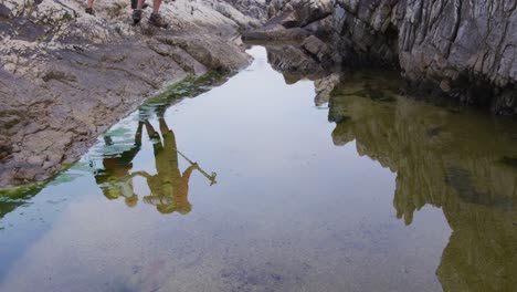 reflejo de una pareja de excursionistas mayores con mochilas caminando por las rocas mientras caminan.