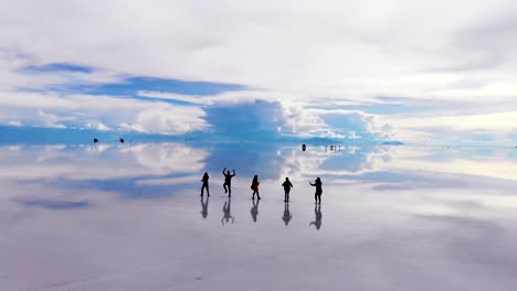 在玻利維亞的uyuni salt flats湖上跳舞的 siluetted 人的空中影像