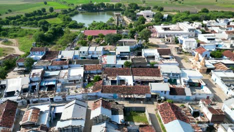 Indian-Village,-Country-side-drone-shot-with-lake-in-the-background,-dolly-in-shot-of-a-small-village-community,-Rural-India,-old-houses,-Temple,-India-country-side