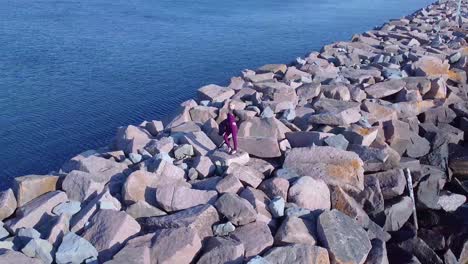 Aerial-young-women-standing-on-rocks-near-coastline