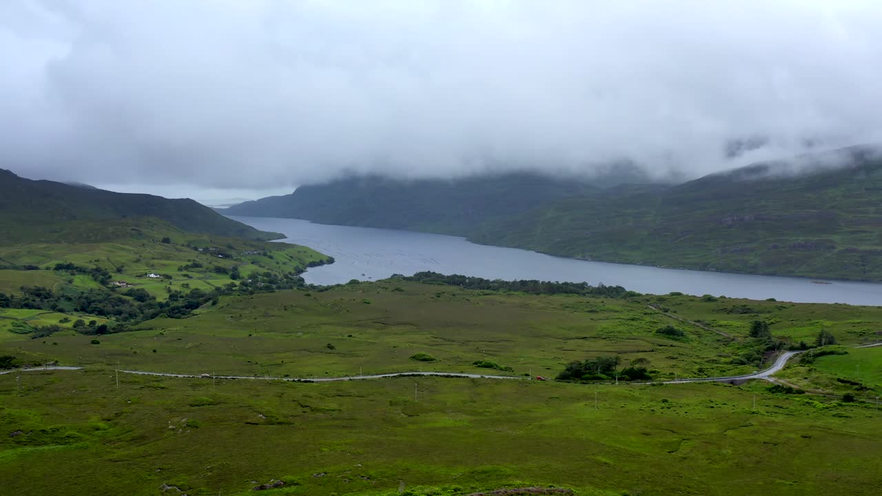 Killary Fjord, Leenane, Connemara, County Galway, July 2021. Drone looks west out towards the Atlantic while slowly tracking north as low-hanging clouds drift across the mountains