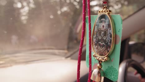 Hindu-or-Indian-lucky-charms-objects-hanging-from-the-rear-view-mirror-of-a-car,-good-luck-background