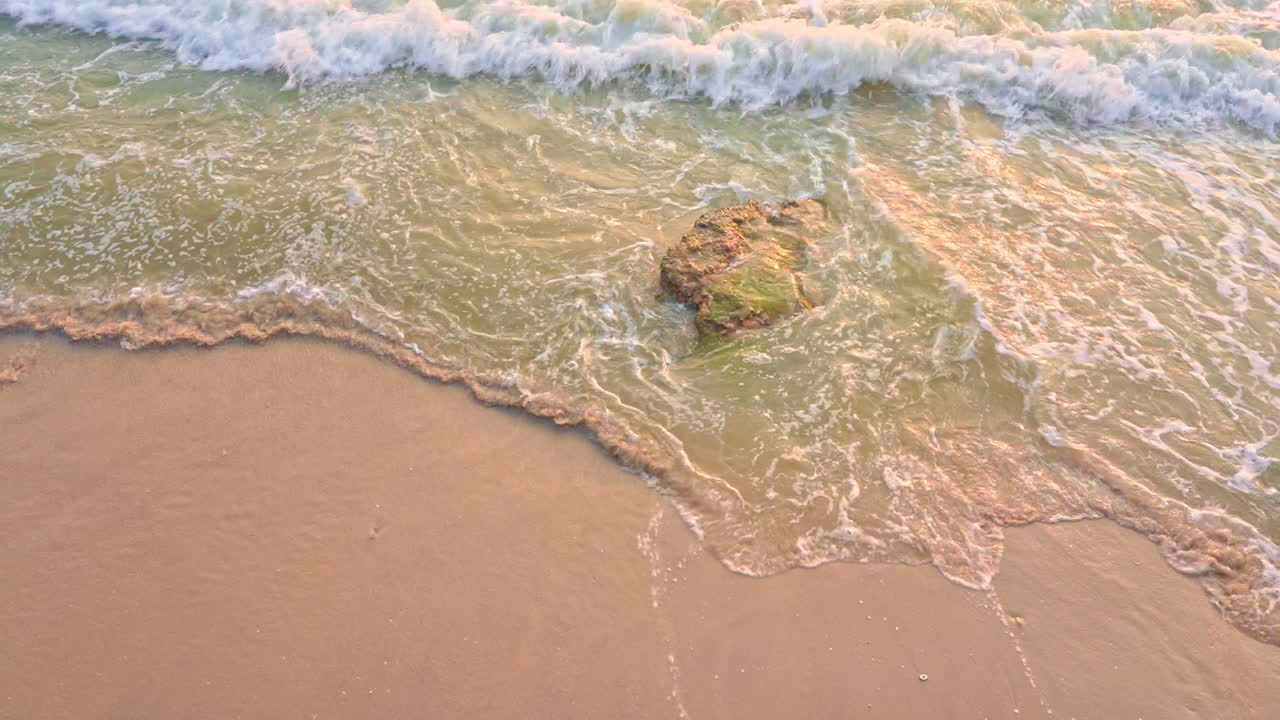 Top down view over coastline, turquoise blue water crashing on the shore with rock in pristine tropical beach