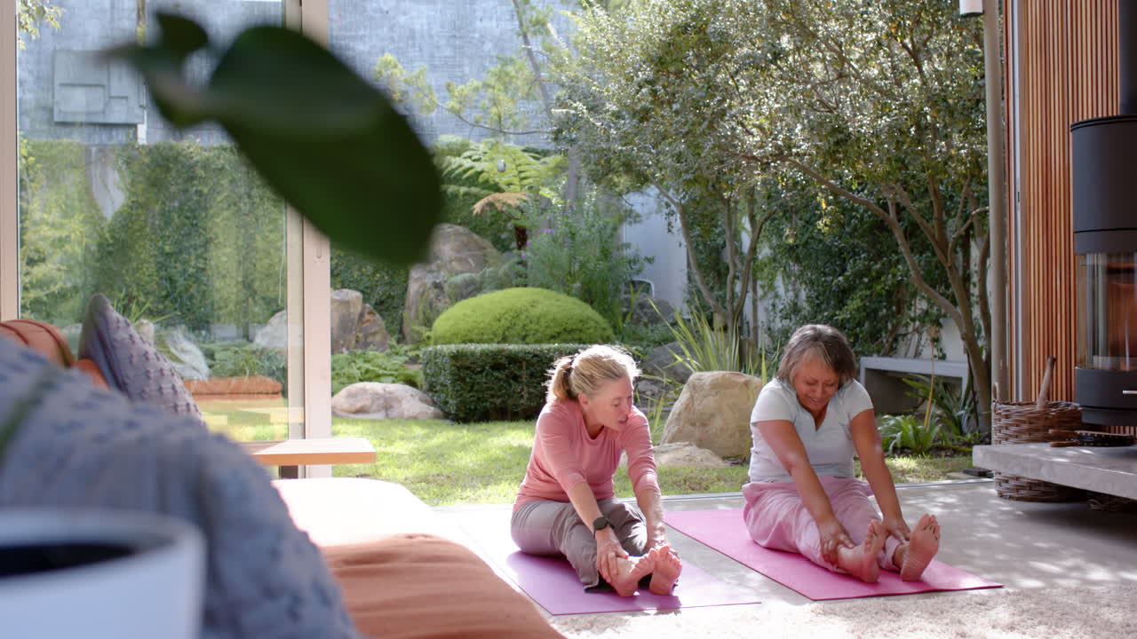 Stretching on yoga mats, multiracial female friends exercising together in garden