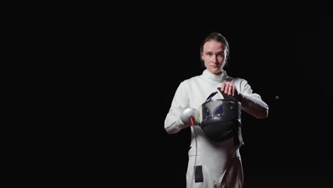 woman in fencing uniform and mask prepares for a match