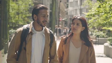 muslim couple on date talking as they walk along city street together 1