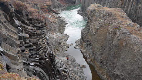 a person walking by the river in a canyon with grey basalt columns