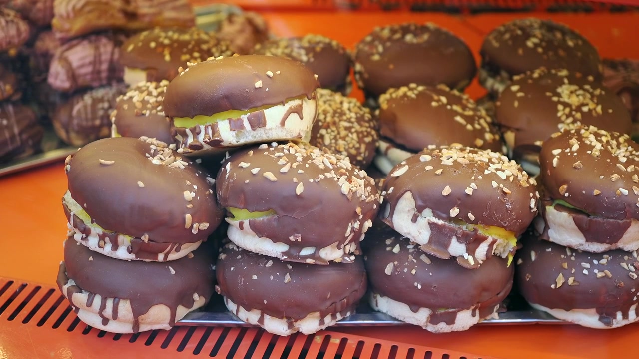 Deliciosos pasteles cubiertos de chocolate exhibidos en el escaparate de una panadería