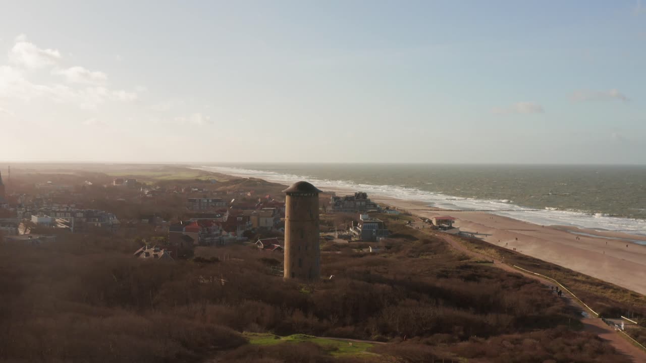 Drone shot of a water tower located in the dunes revealing the beach and the sea