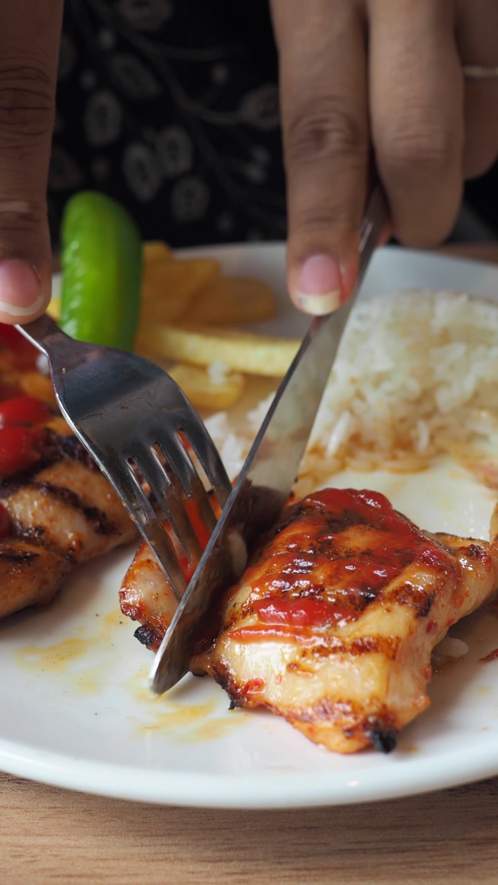 Close-up of Grilled Chicken with Rice and Fries Being Cut