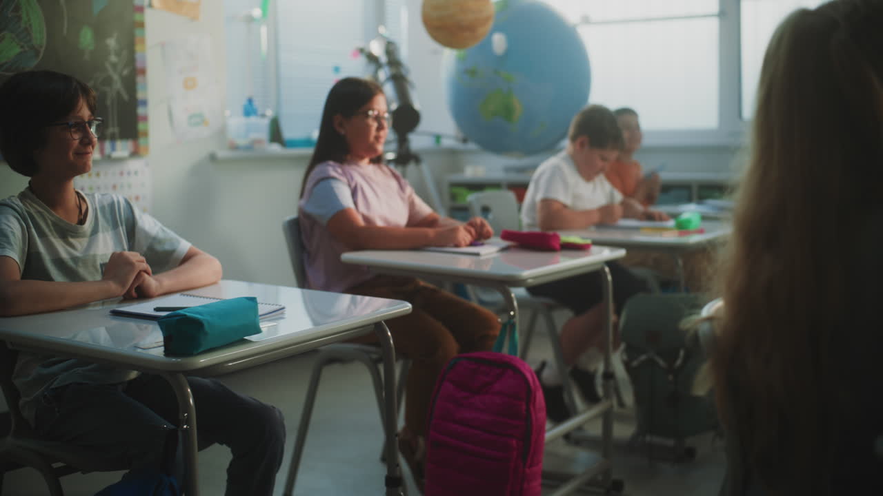 Primary School Children Sitting at Desks Writing School Exam or Doing Tasks in Notebooks