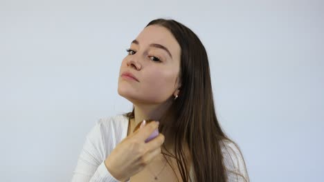 serious young and beautiful attractive woman applying cosmetic makeup on her face in the morning with the brush in front of a white background