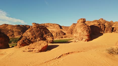 green oasis near rock formation in al ula, saudi arabia on a sunny day - aerial drone view