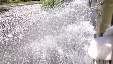 vehicle driving through a water puddle on a dirt road