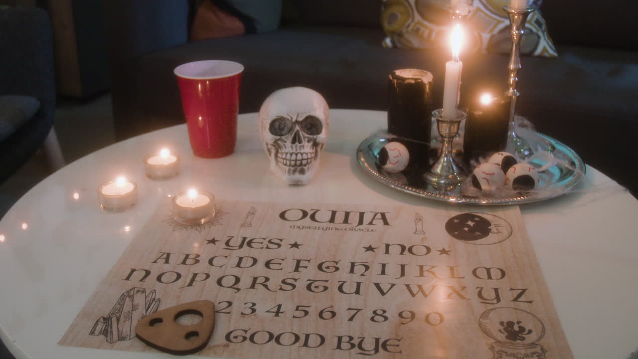 Ouija board with candles and skull on a table
