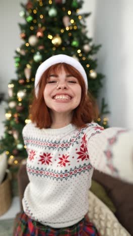 una mujer tomando una selfie junto a un árbol de navidad.