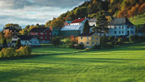 a picturesque village with colorful houses nestled on a green hillside, surrounded by the vibrant hues of autumn