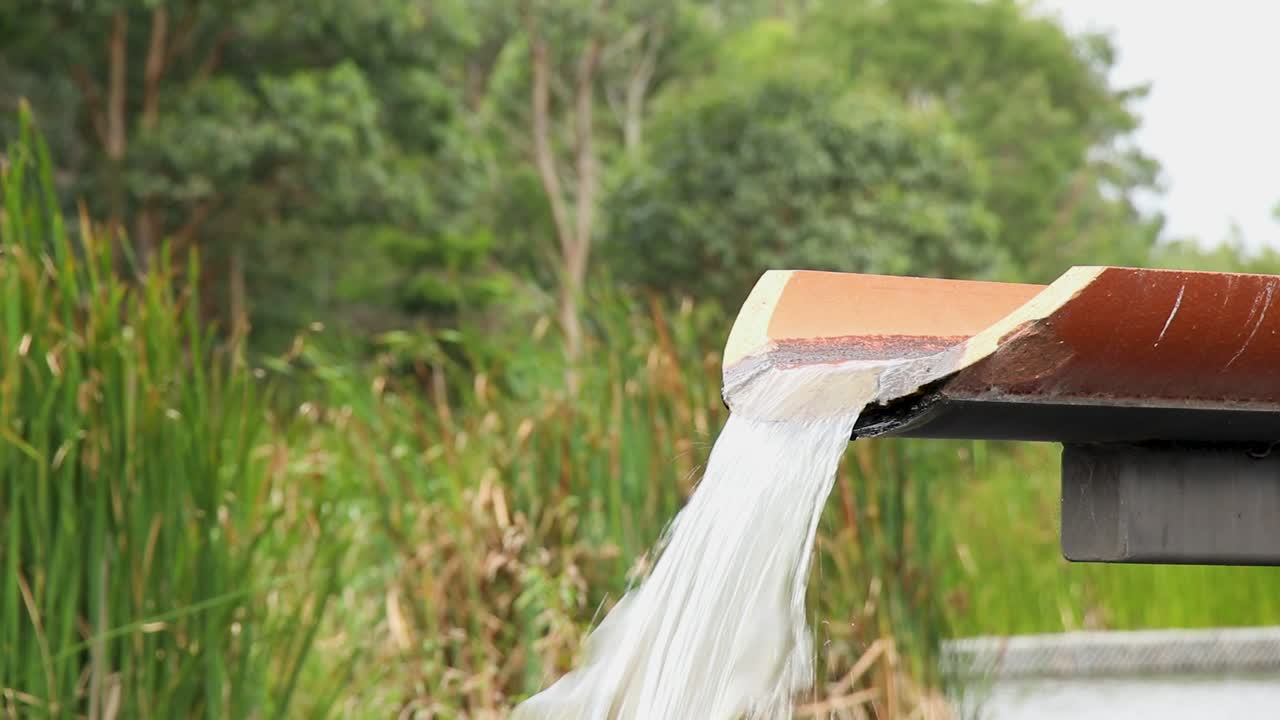 Water filling wet land pond from elevated concrete channel drain.
