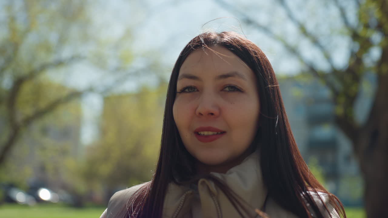 화창한 공원에서 햇볕을 즐기는 여성, 밝은 미소로 야외에 있는 젊은 여성, 화창한 날에 꽃 향기를 맡는 젊은 여성, 봄꽃을 감상하며 햇볕을 쬐는 젊은 여성