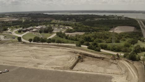un camión volquete entrega una carga de suciedad mientras un camión arrastra una carga al sitio de construcción