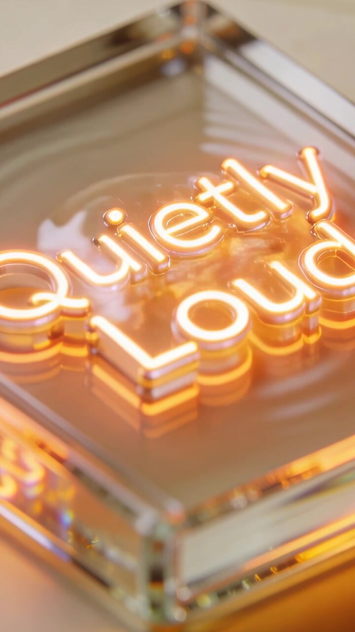 Vertical video: Tilting camera revealing Quietly Loud neon on tabletop, highlighting acrylic layers