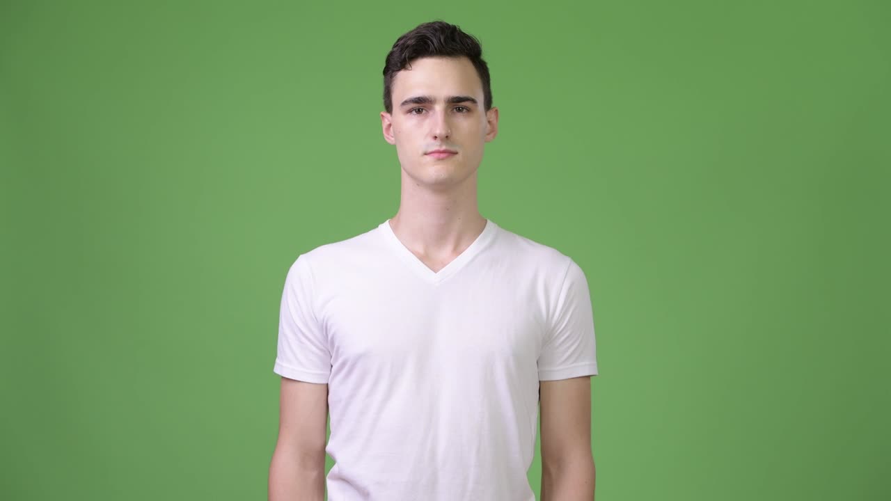 Young happy handsome man smiling against green background