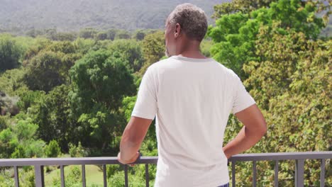hombre afroamericano de alto nivel mirando la vista en su balcón