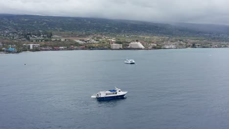 Aerial-close-up-panning-shot-around-a-ferry-boat-docked-at-a-submarine-off-the-coast-of-Kailua-Kona,-Hawai'i