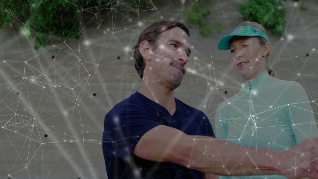 Male colleague shaking hands with female colleague, showing tech network overlay on climbing wall