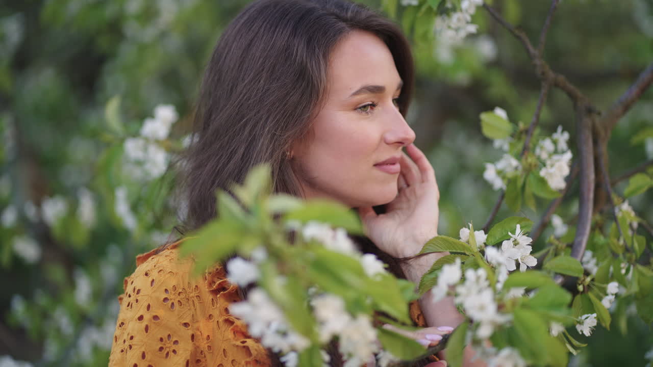 hermosa joven está posando con un cerezo en flor en el jardín en el día de primavera retrato femenino en el huerto