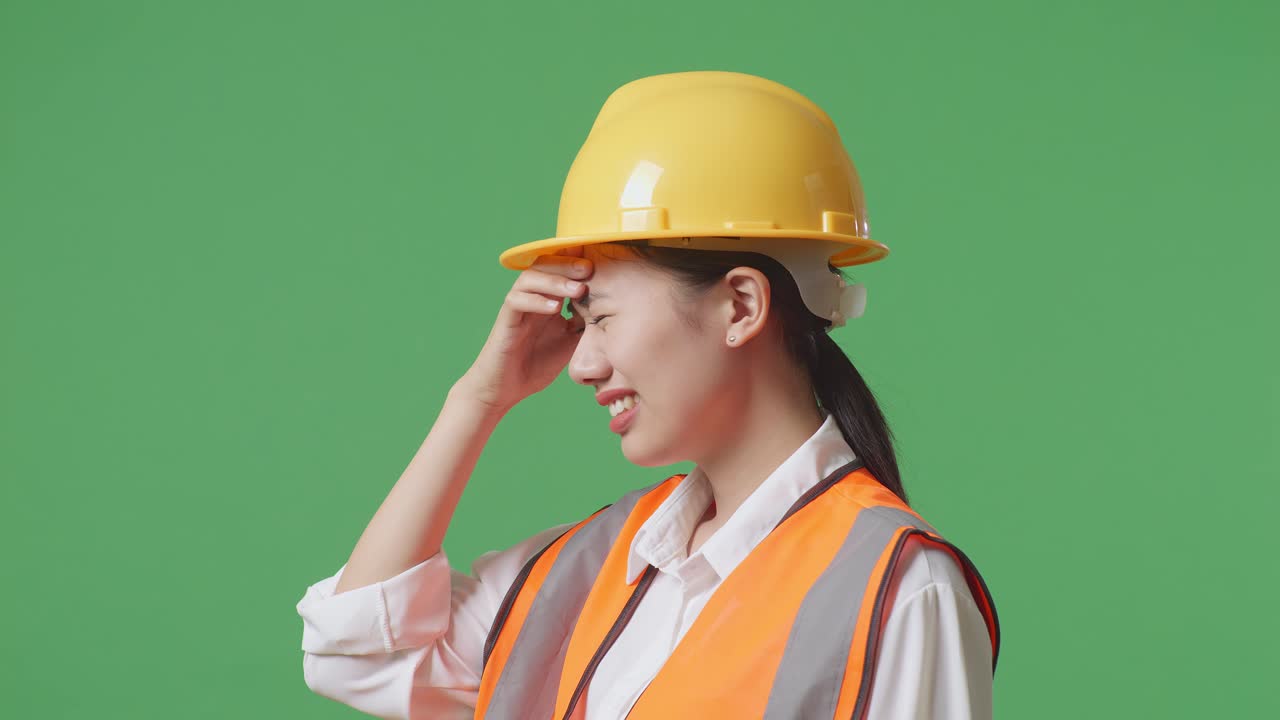 Close Up Side View Of Asian Female Engineer With Safety Helmet Having A Headache While Working In The Green Screen Background Studio