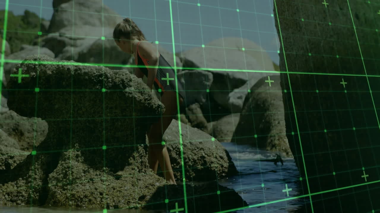 Exploring rocky shore, child interacting with digital grid overlay animation