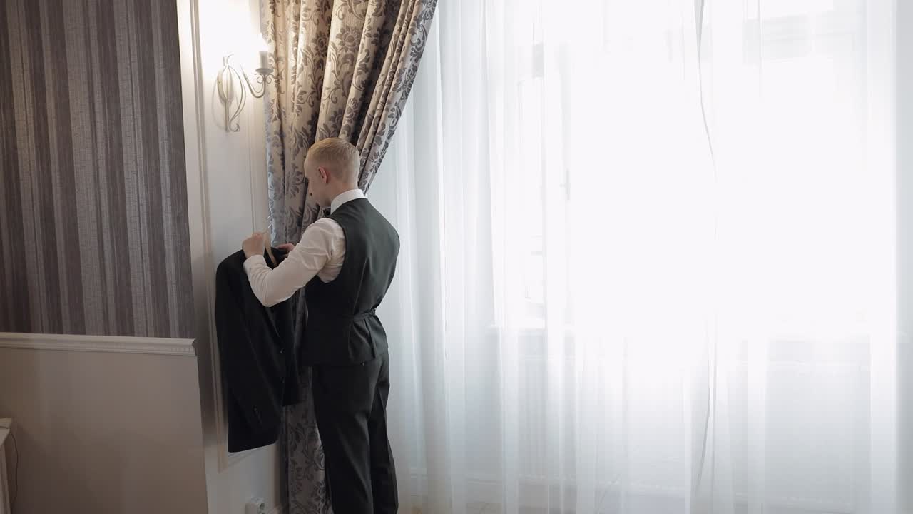 예쁜 세련된 신랑이 초록색 재 ⁇ 을 입고 거실에서 집에, 느린 동작 실내 초상화